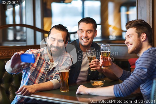 Image of friends taking selfie and drinking beer at bar