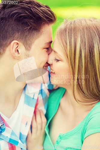 Image of smiling couple kissing and hugging in park