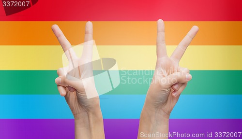 Image of hands showing peace sign over rainbow stripes