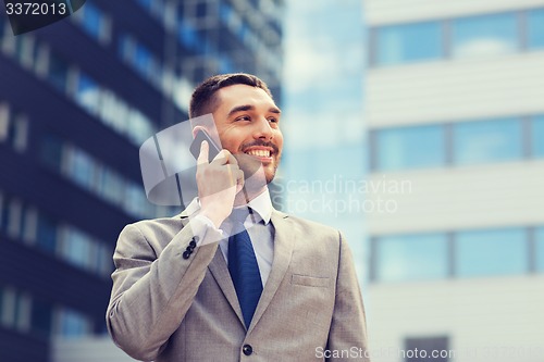 Image of smiling businessman with smartphone outdoors