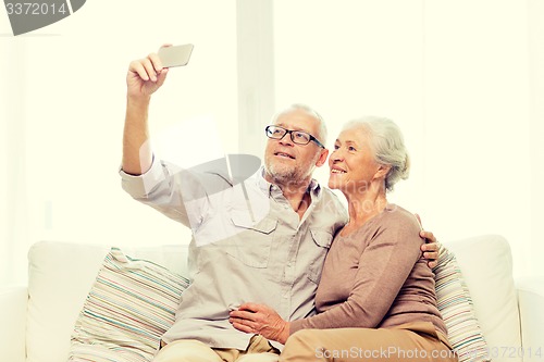 Image of happy senior couple with smartphone at home