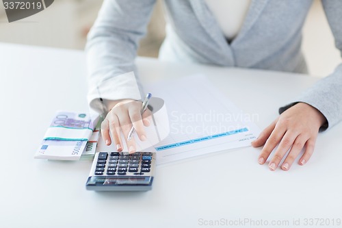 Image of close up of hands counting money with calculator