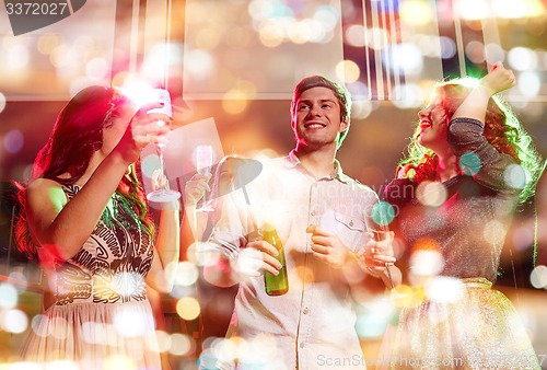 Image of smiling friends with wine glasses and beer in club