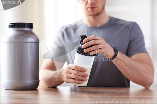 Image of close up of man with protein shake bottle and jar