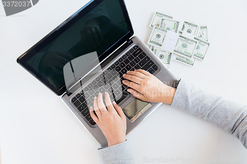 Image of close up of woman hands with laptop and money