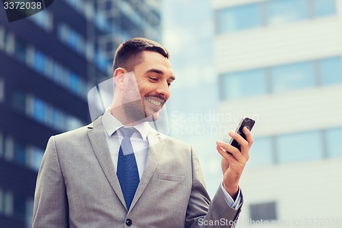 Image of smiling businessman with smartphone outdoors