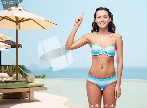 Image of happy woman in bikini swimsuit pointing finger up