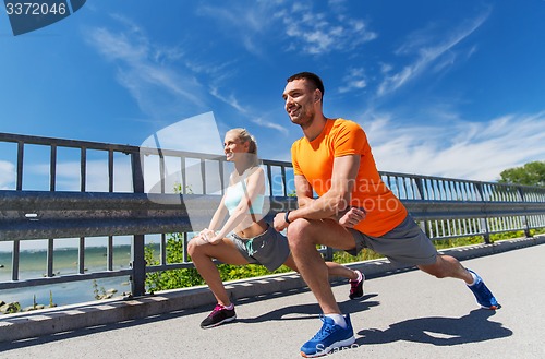 Image of smiling couple stretching outdoors