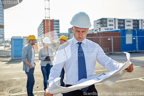 Image of architect with blueprint on construction site