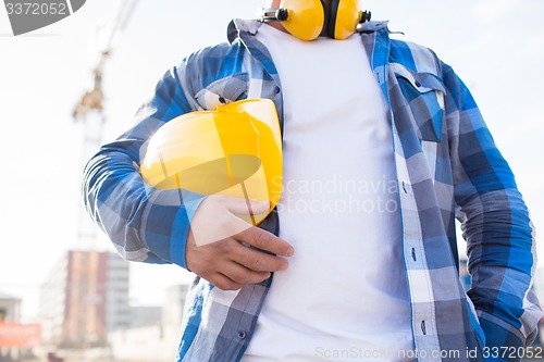 Image of close up of builder holding hardhat on building