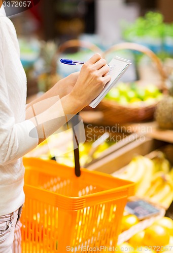 Image of close up of woman writing to notepad in market