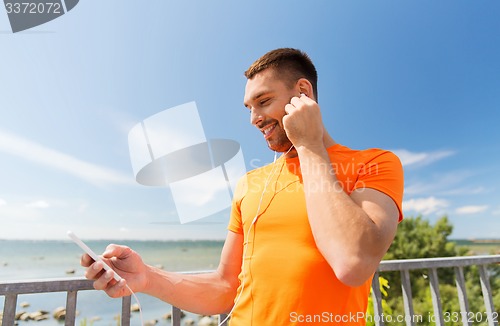 Image of smiling young man with smartphone and earphones