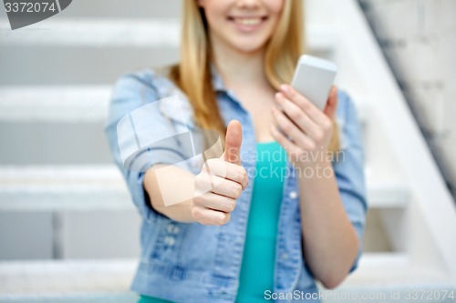 Image of female with smartphone showing thumbs up