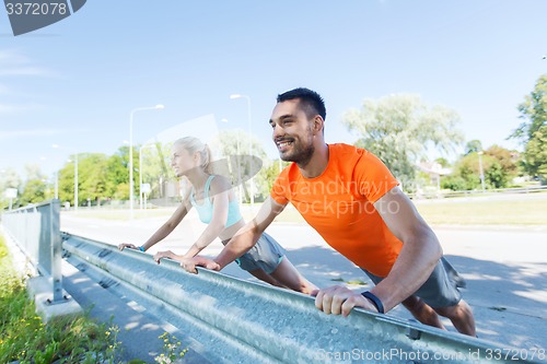 Image of close up of happy couple doing push-ups outdoors