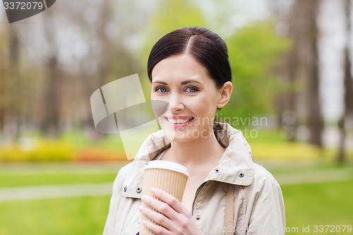 Image of smiling woman drinking coffee in park