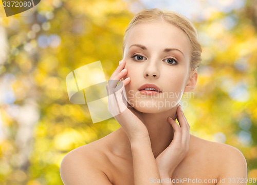 Image of beautiful young woman touching her face
