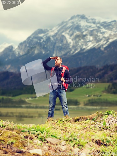 Image of tourist with beard and backpack looking far away