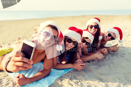 Image of group of friends in santa hats with smartphone