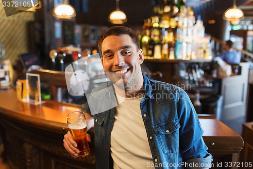 Image of happy man drinking beer at bar or pub