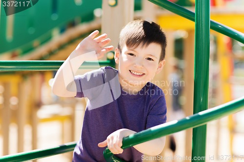 Image of happy little boy climbing on children playground