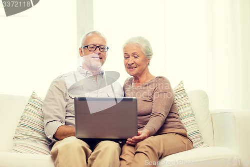 Image of happy senior couple with laptop at home