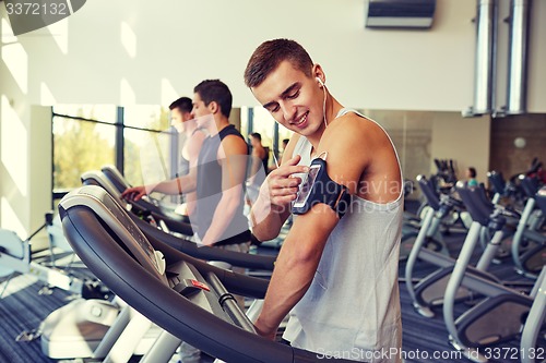 Image of man with smartphone exercising on treadmill in gym