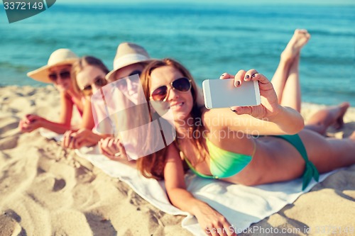 Image of close up of smiling women with smartphone on beach