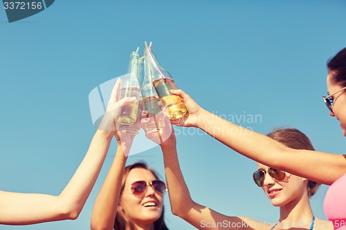 Image of close up of happy young women clinking bottles