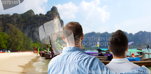 Image of close up of male gay couple hugging on beach