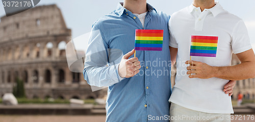 Image of close up of male gay couple with rainbow flags