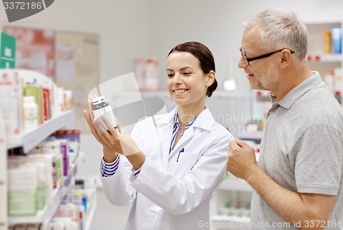 Image of pharmacist showing drug to senior man at pharmacy