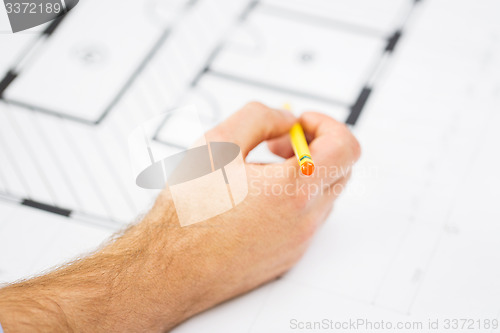 Image of close up of male hand with blueprint and pencil