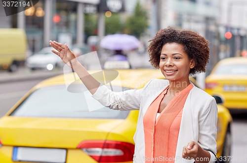 Image of happy african woman catching taxi