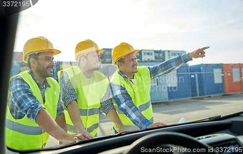 Image of close up of builders with blueprint on car hood