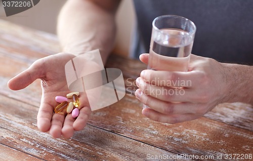 Image of close up of male hands holding pills and water