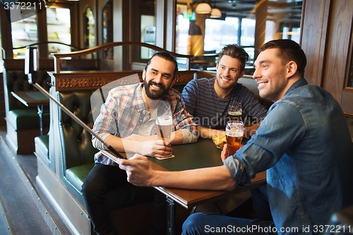 Image of friends taking selfie and drinking beer at bar