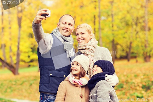 Image of happy family with camera in autumn park