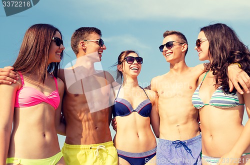 Image of smiling friends in sunglasses on summer beach