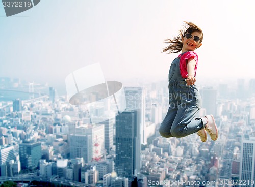 Image of happy little girl jumping over city background