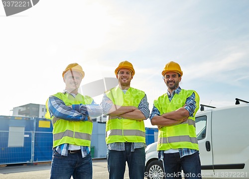 Image of happy male builders in high visible vests outdoors