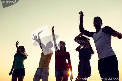 Image of smiling friends dancing on summer beach