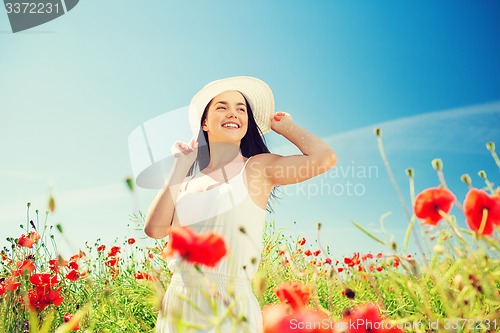 Image of smiling young woman in straw hat on poppy field