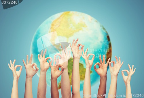 Image of human hands showing ok sign over earth globe