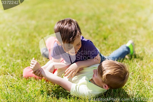 Image of happy little boys fighting for fun on grass