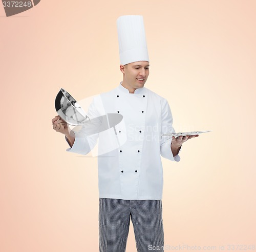 Image of happy male chef cook opening cloche