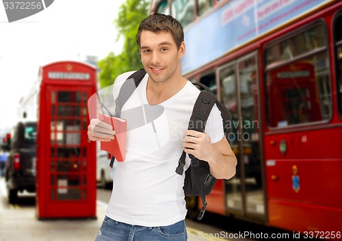 Image of happy young man with backpack and book travelling