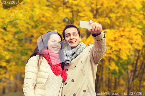 Image of smiling couple hugging in autumn park