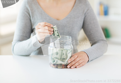 Image of close up of woman hands and dollar money in jar