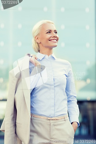 Image of young smiling businesswoman over office building