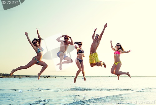 Image of smiling friends in sunglasses on summer beach